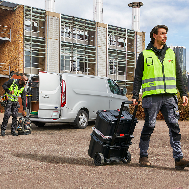 Electricians in high-vis vests unload tools from a van at a job site, highlighting wrong business insurance cover for electricians.